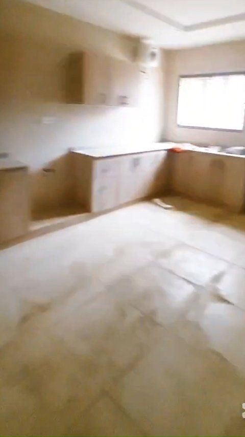 An empty kitchen with a sink , cabinets and a window.