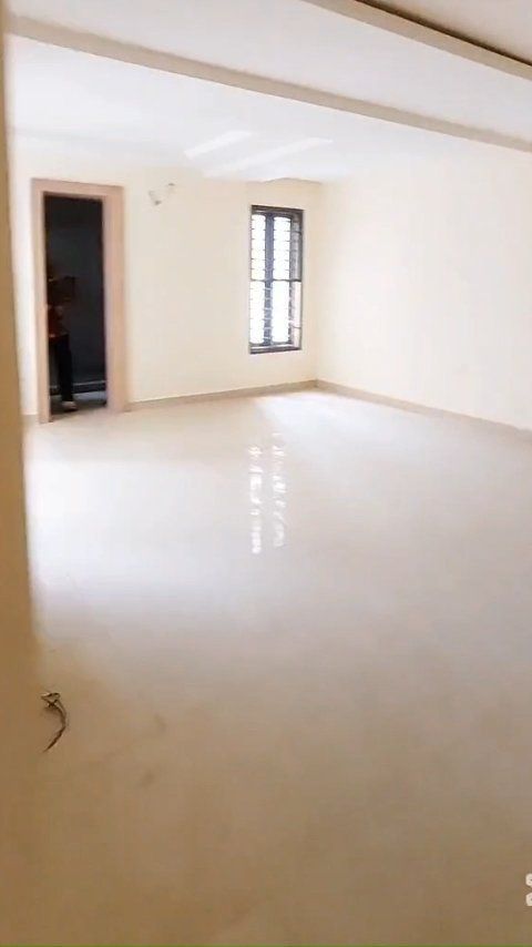 A large empty room with two windows and a door.