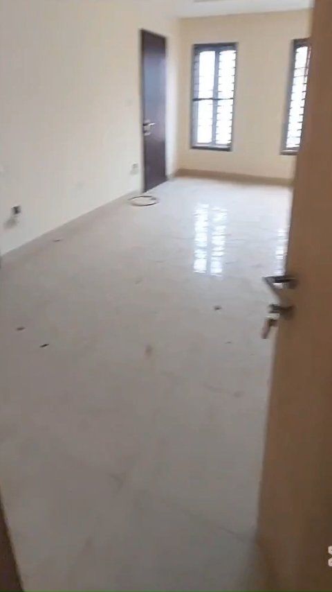 An empty room with a door and two windows.