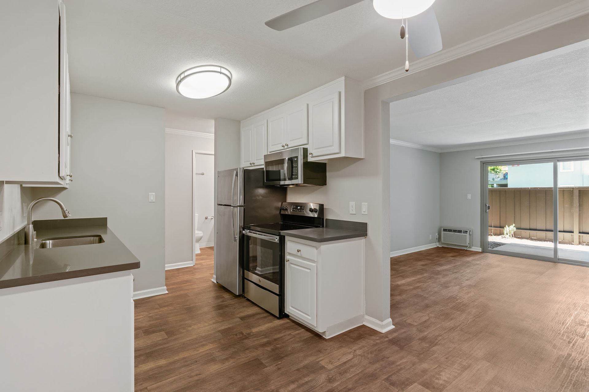 Kitchen with white cabinets, gray countertops, stainless steel appliances, and an open living area.