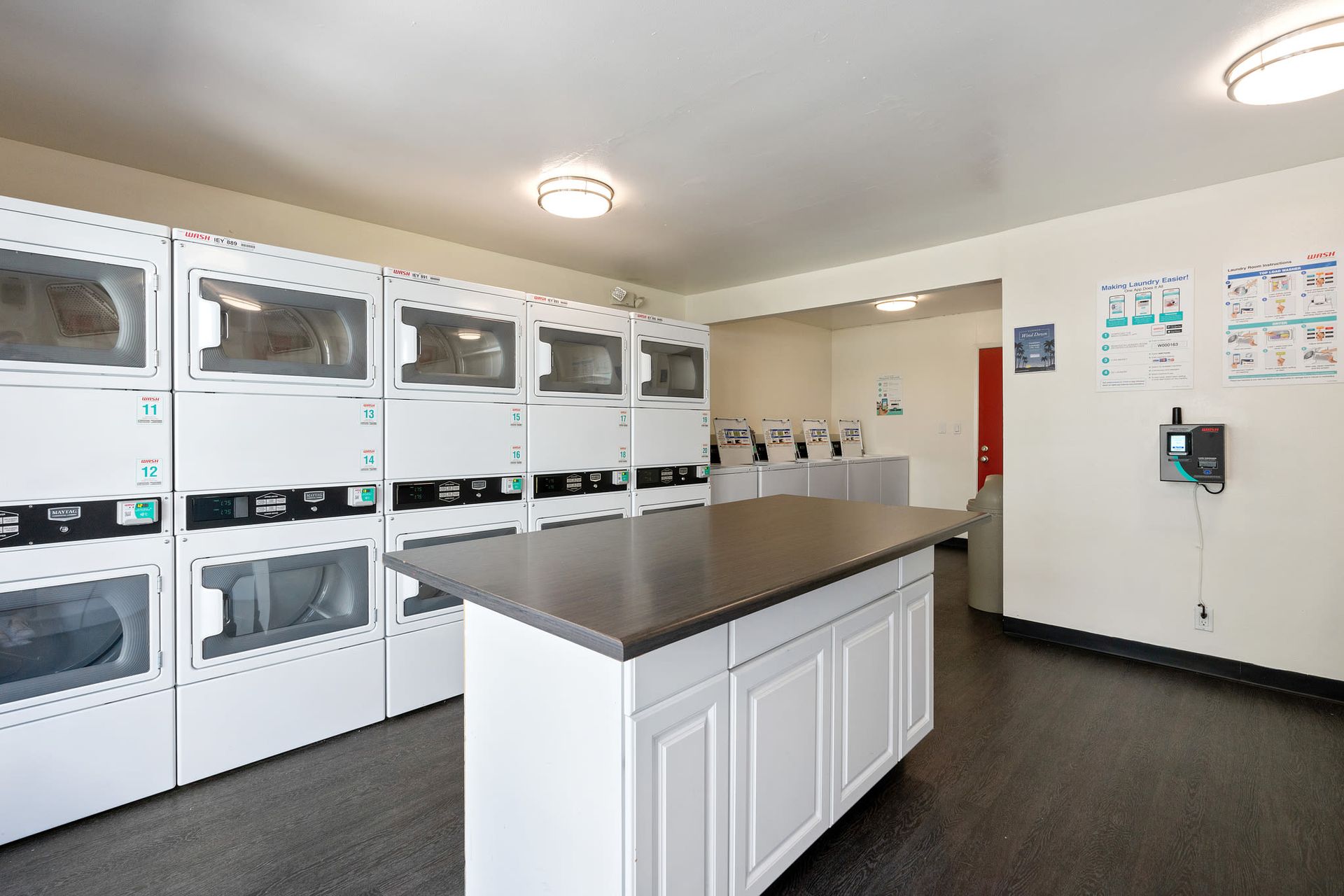Shared laundry room with stacked front-load washers and a central folding island.