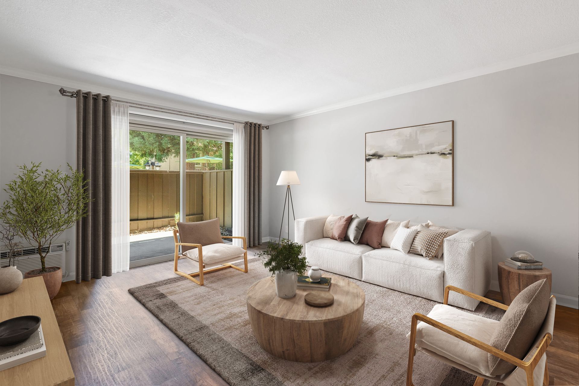 Bright living room in an apartment with sofa, chairs, rug, and sliding glass door.