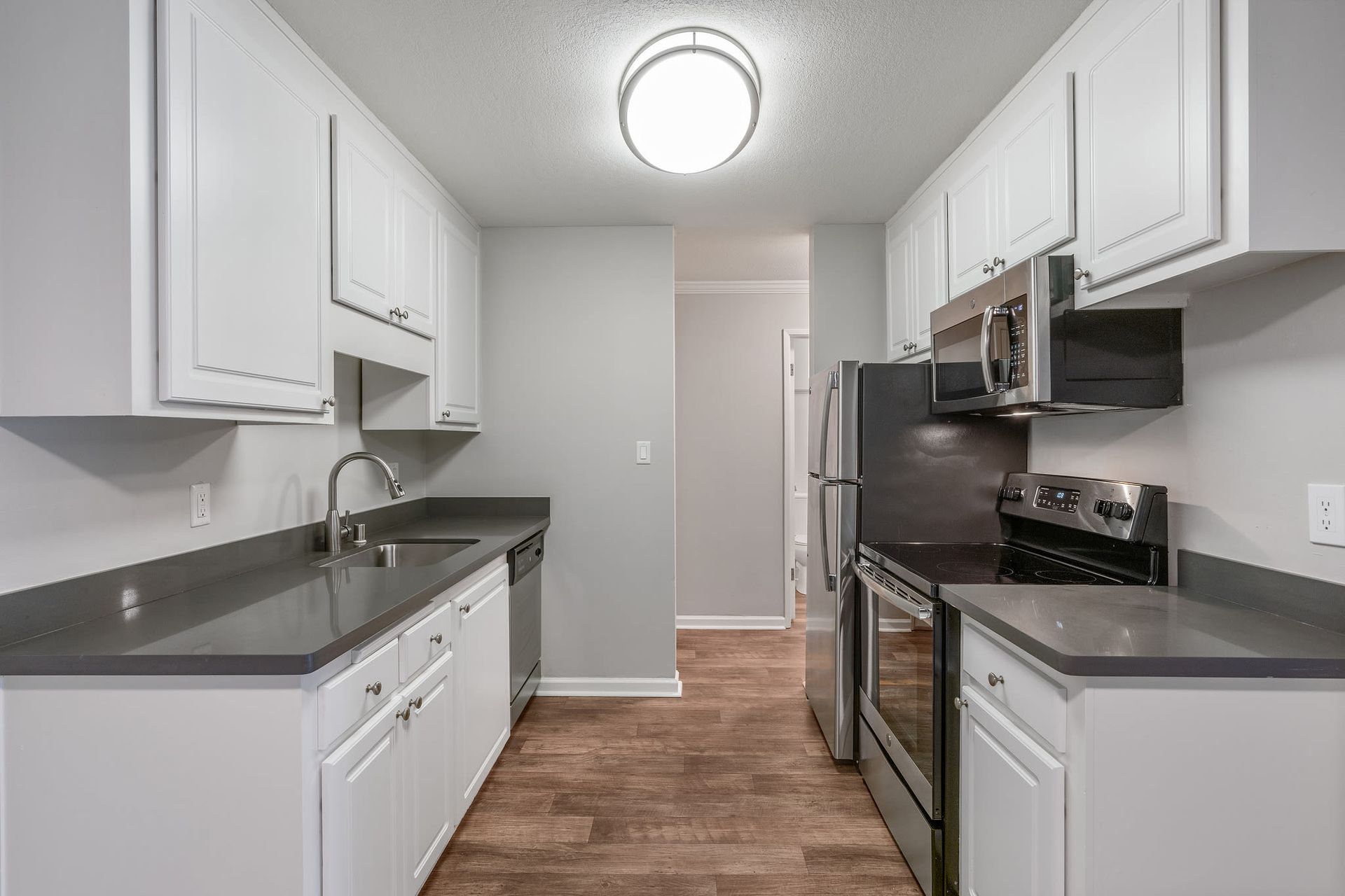 Galley-style kitchen with white cabinets, gray countertops, and stainless steel appliances.