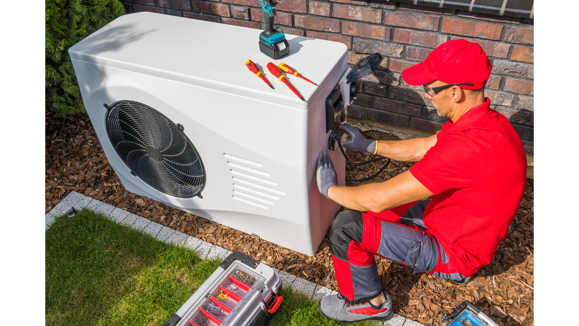 A man is working on a heat pump outside of a house.