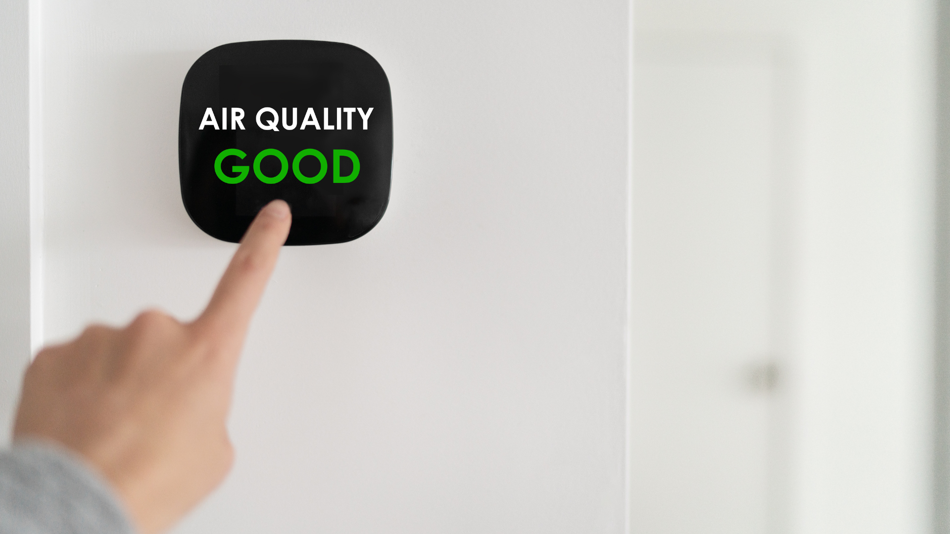 A person is pressing a button on a wall that says `` air quality good ''.