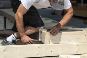 A man is working on a piece of wood with a clamp.