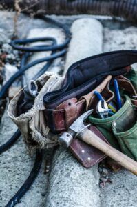 A tool bag filled with tools and a hammer.