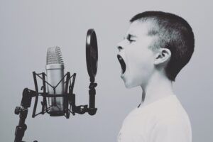 A young boy is singing into a microphone in a black and white photo.