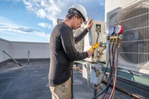 A man is working on an air conditioner on a rooftop.