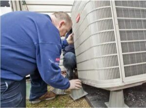 A man is working on an air conditioner outside of a house.