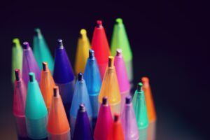 A bunch of colorful pens are sitting on a table.