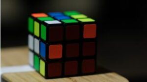A colorful rubik 's cube is sitting on a wooden table