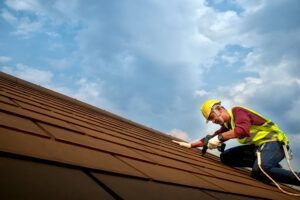A man is working on a roof with a hammer.