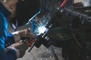 A man is welding a piece of metal in a factory.