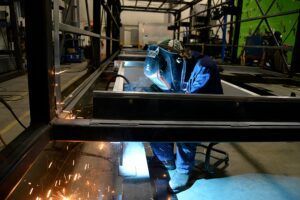 A man is welding a piece of metal in a factory.