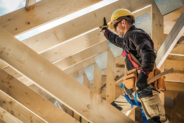 A construction worker is working on a wooden structure.
