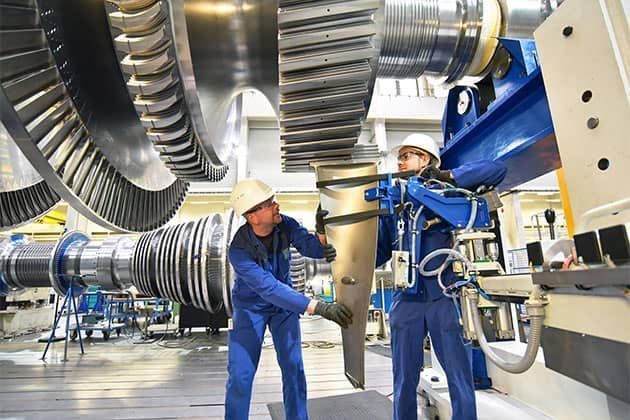Two men are working on a large machine in a factory.