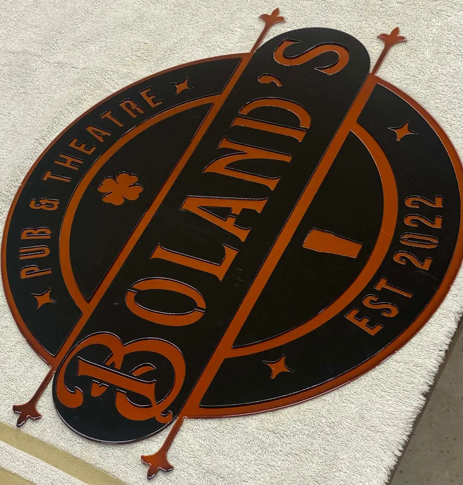 Black and orange sign for Boland's Pub & Theatre, with a shamrock, and EST 2022.