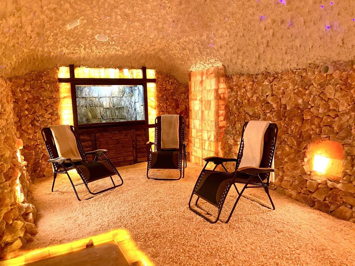 three relaxing lawn chairs inside harmony salt cave filled with floor himalayan salt and natural himalayan salt rocks for the walls inside a soothing 30 square foot salt cave.