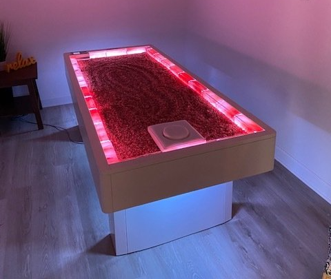 young lady laying on her stomach wearing a towel during a himalayan salt bed therapy session in which she is just relaxing on a bed made with himalayan pink salt.