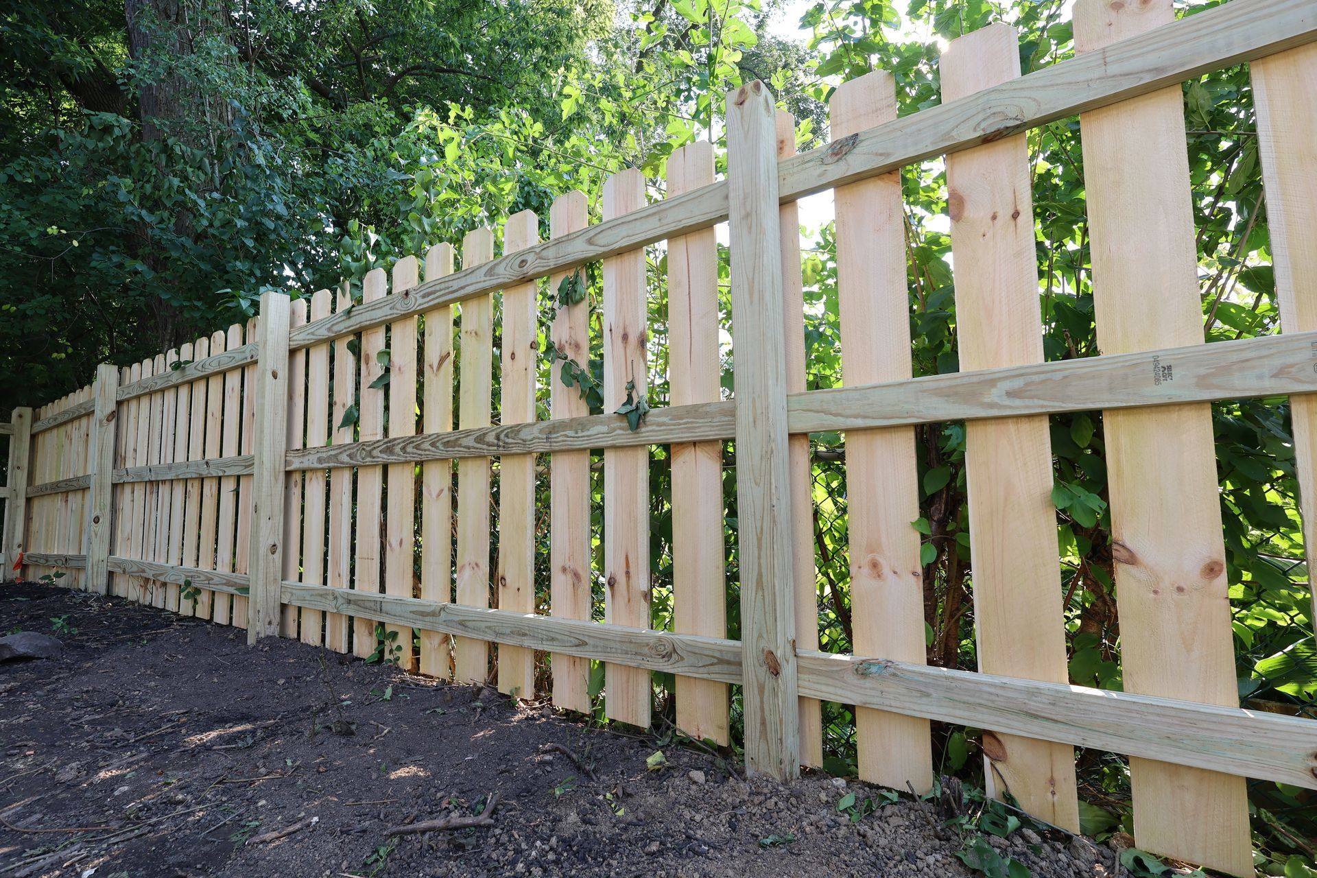 A wooden picket fence with trees in the background