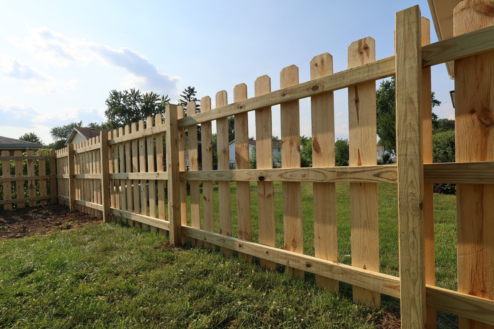 A wooden picket fence surrounds a lush green field.