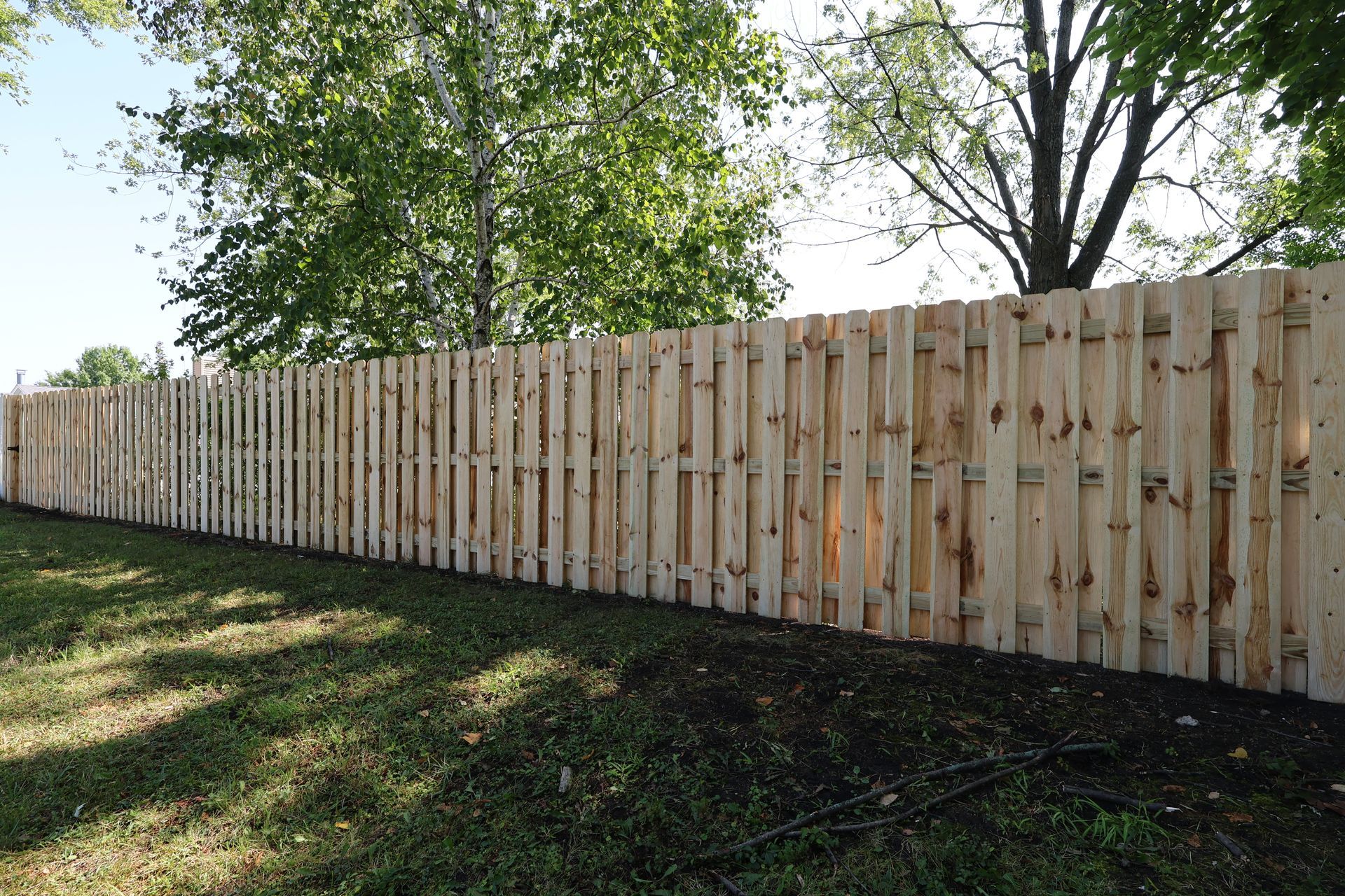 A wooden fence is surrounded by grass and trees