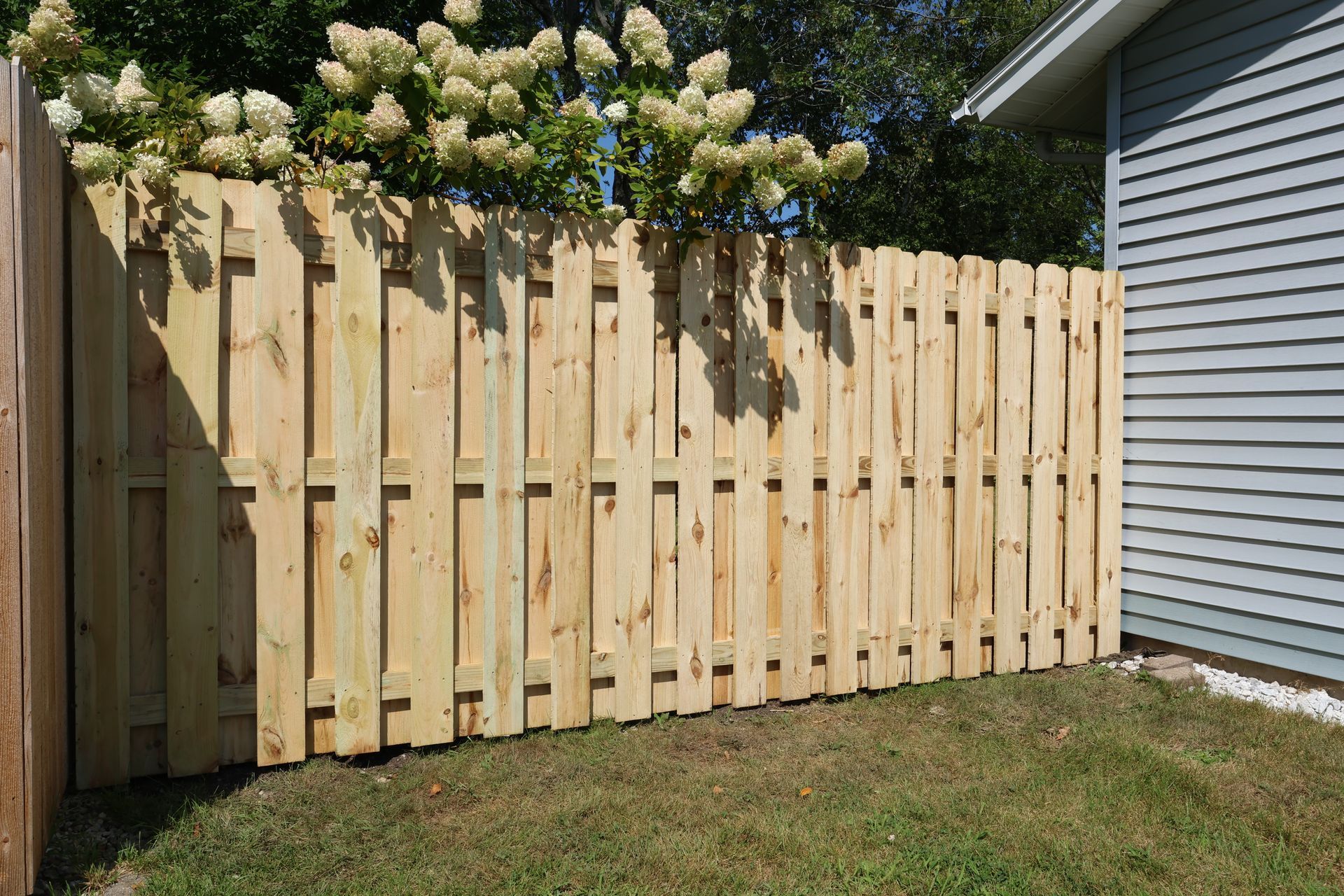 A wooden fence is sitting in the grass in front of a house.