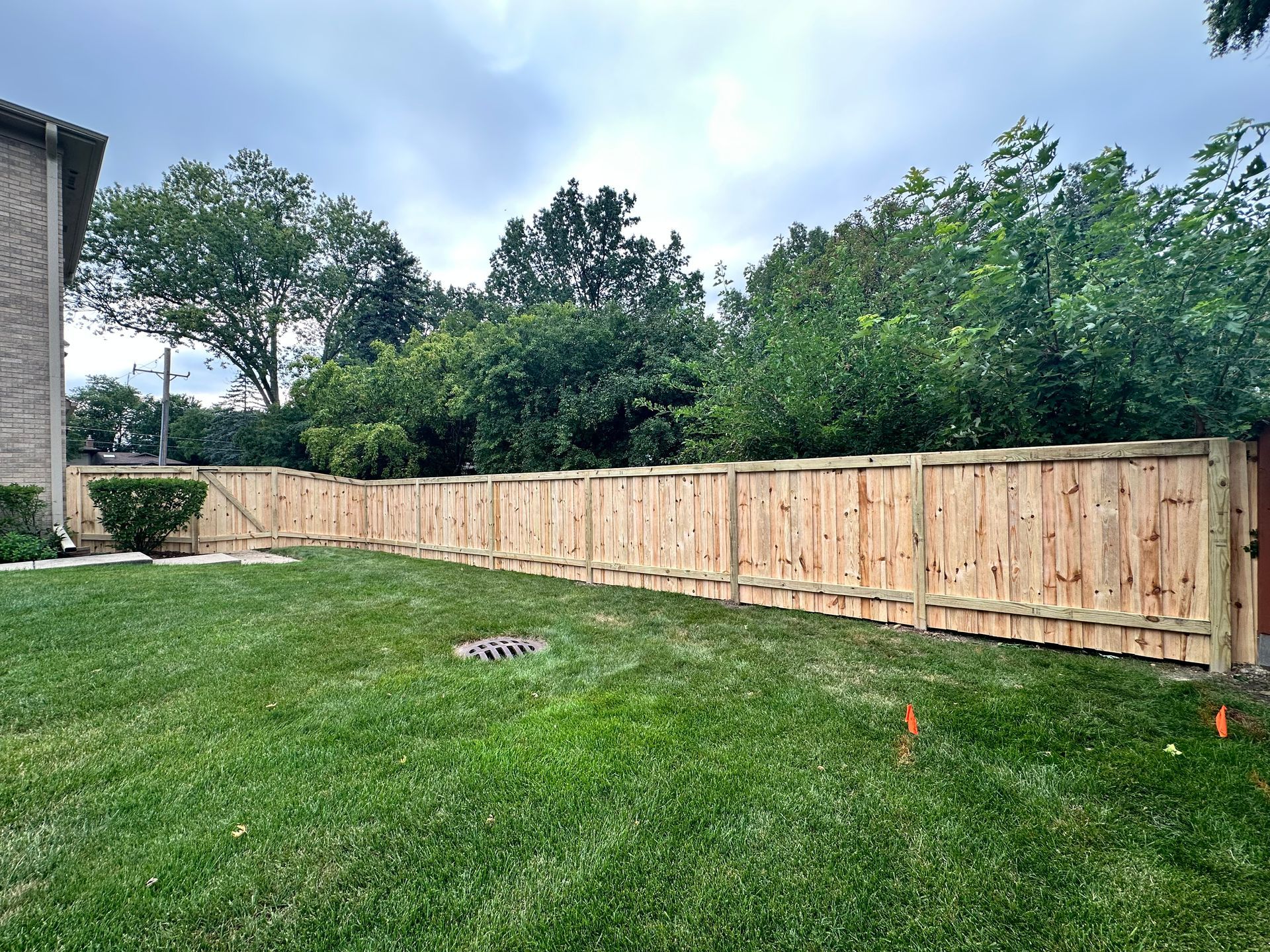 A wooden fence surrounds a lush green lawn in a backyard.
