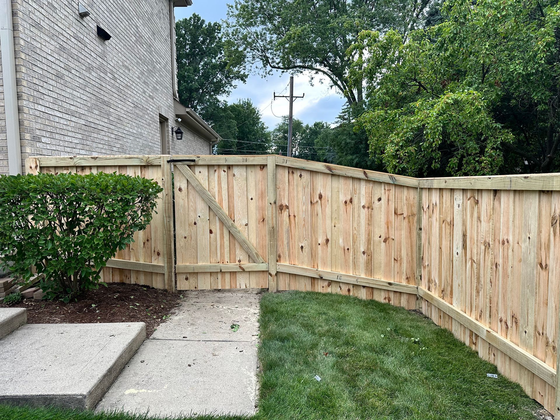 A wooden fence with a gate in the backyard of a house.