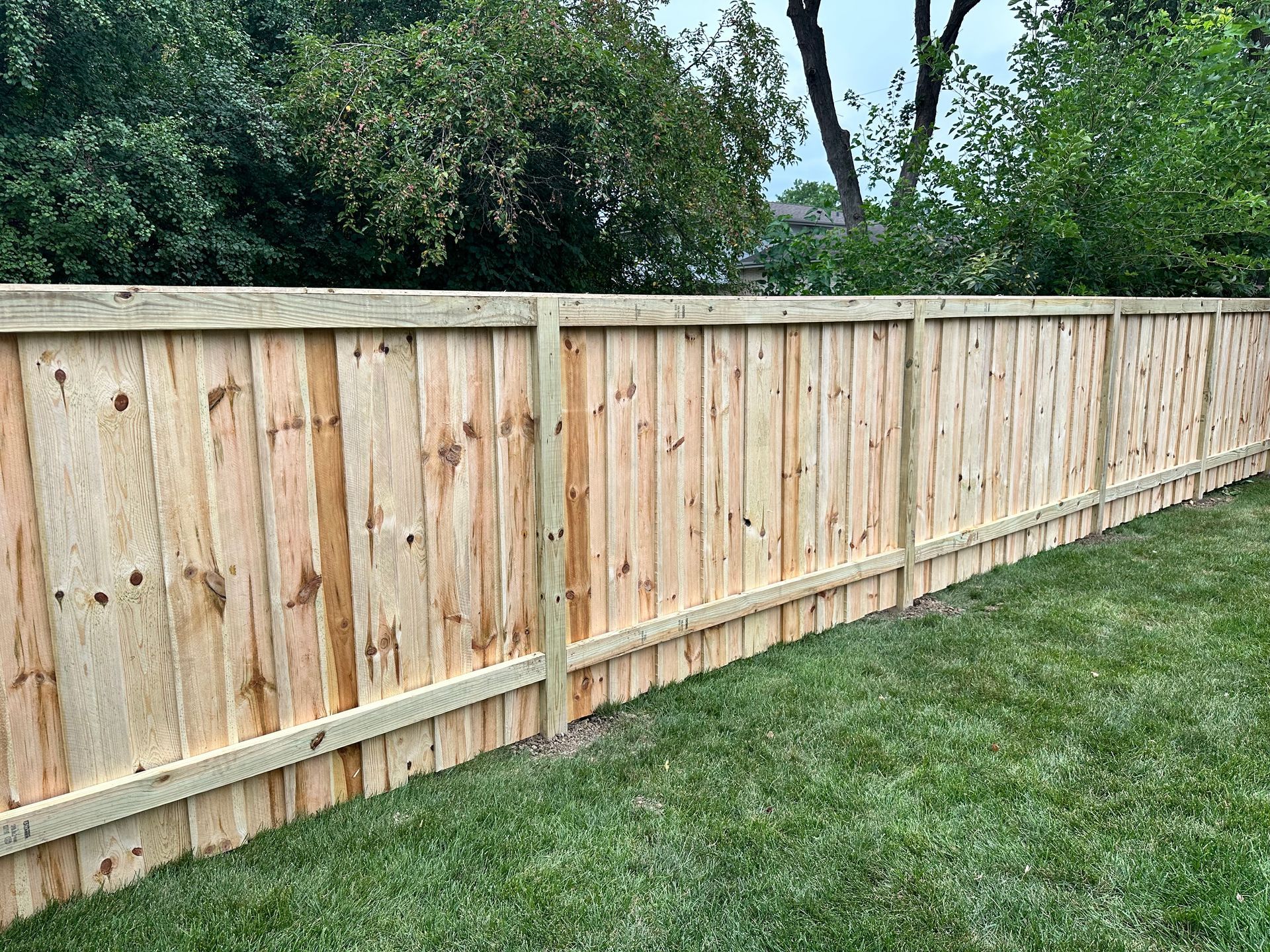 A wooden fence is sitting on top of a lush green lawn.