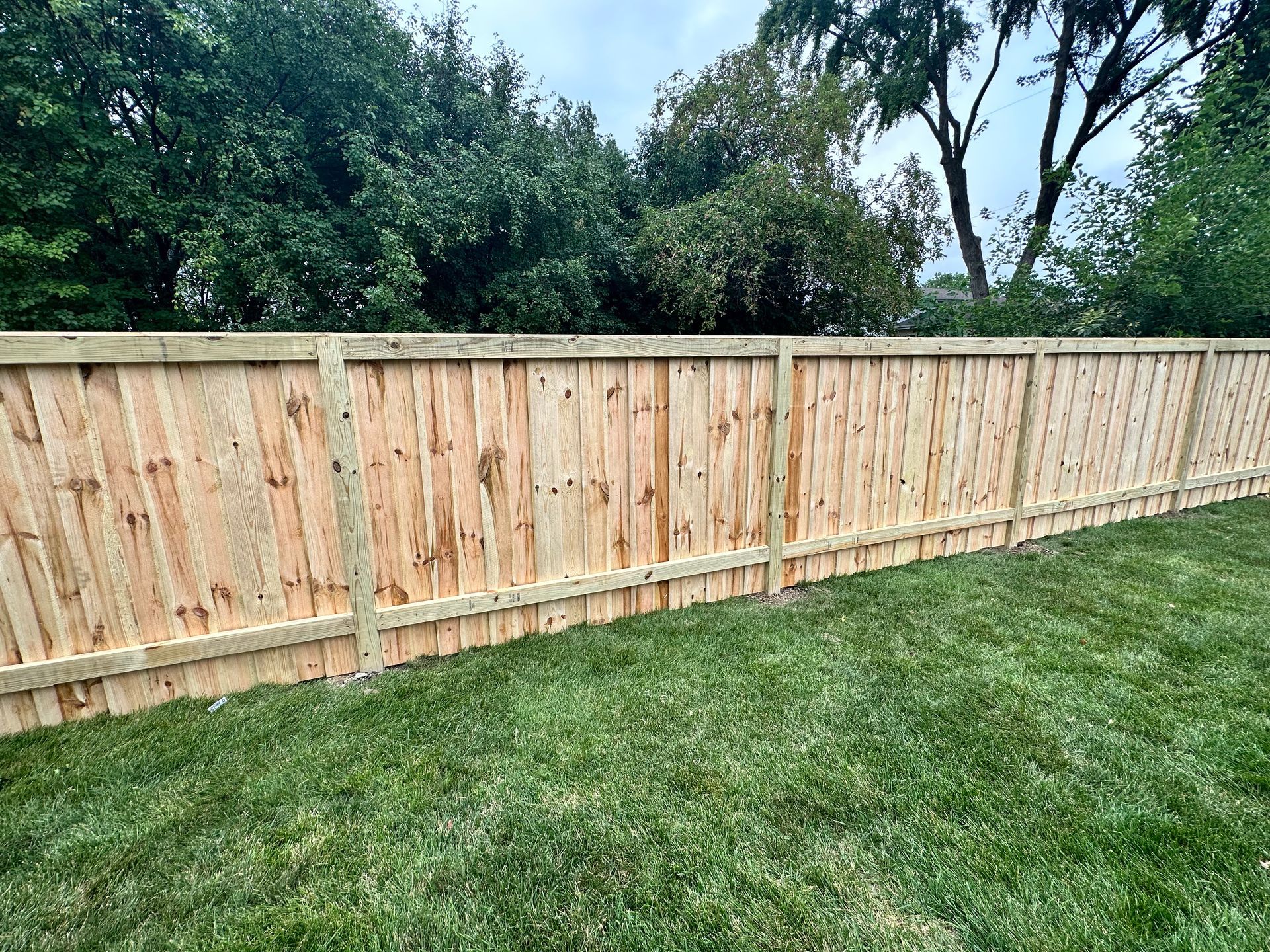 A wooden fence is sitting on top of a lush green lawn.