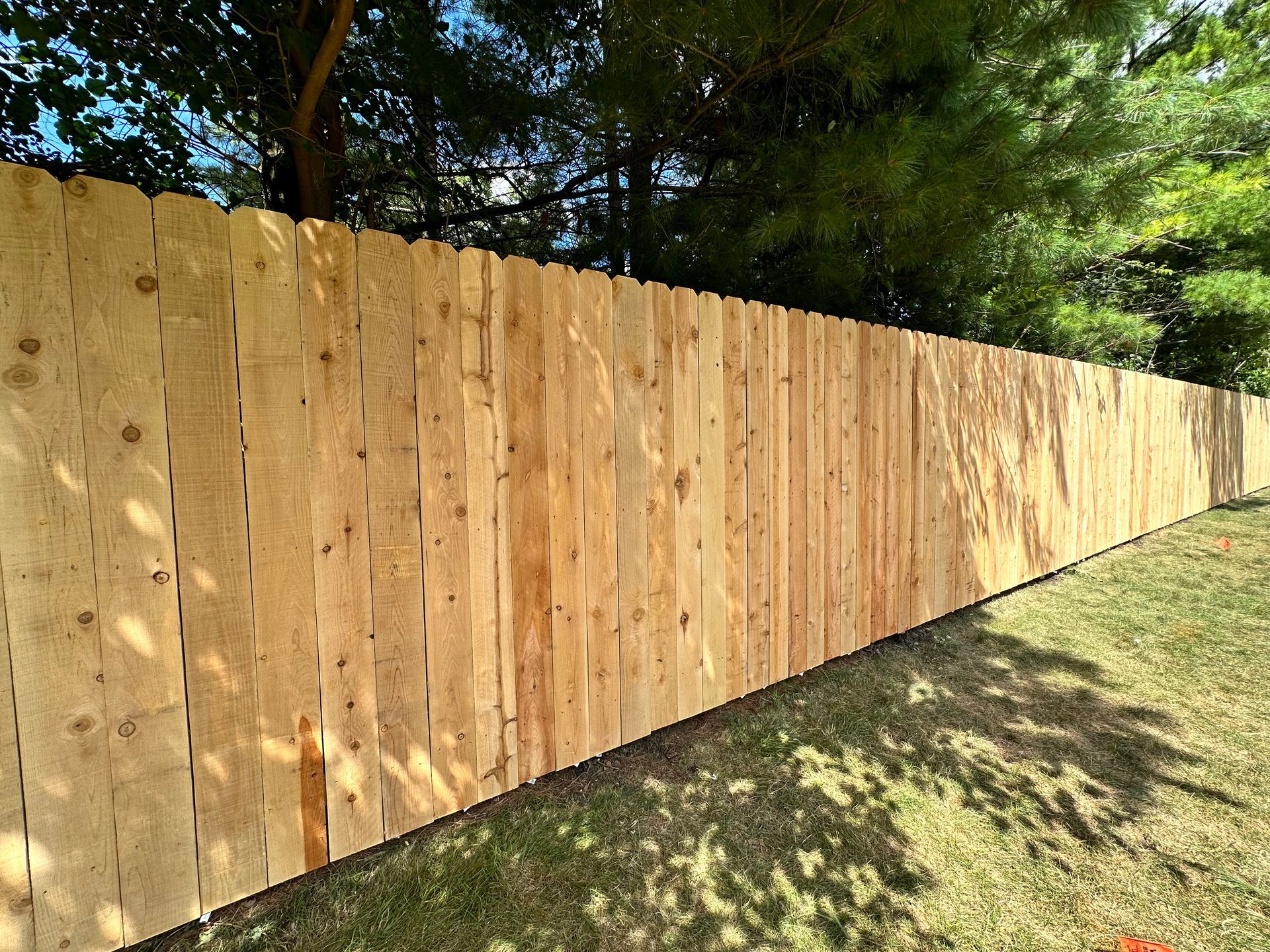 A wooden fence is sitting on top of a lush green field.