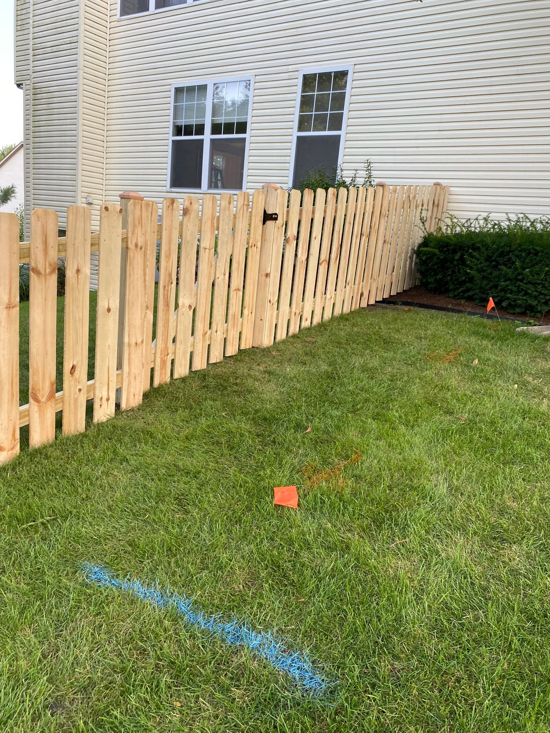 A wooden fence is sitting in the grass in front of a house.