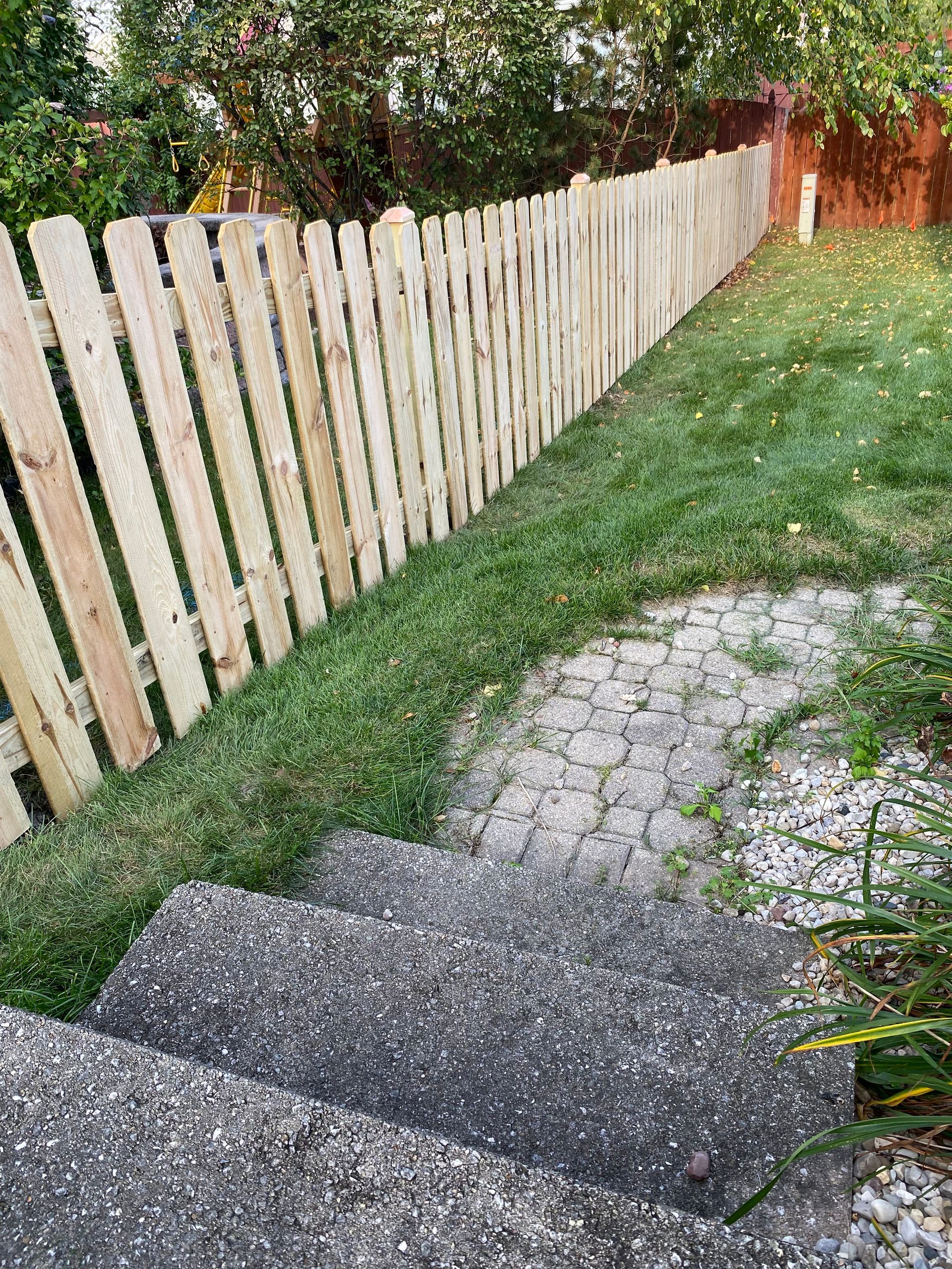 There are stairs leading up to a wooden fence in the backyard.