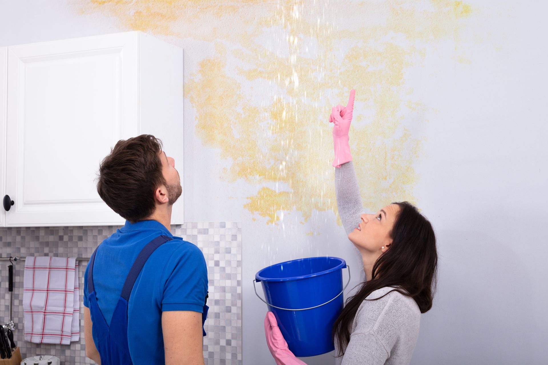 A man and a woman are looking at a leak on the wall.