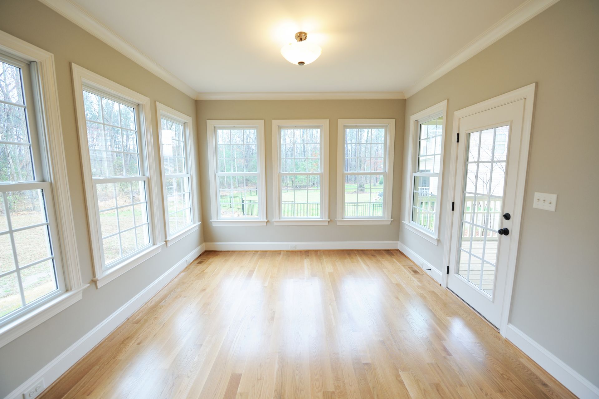 An empty room with hardwood floors and lots of windows.