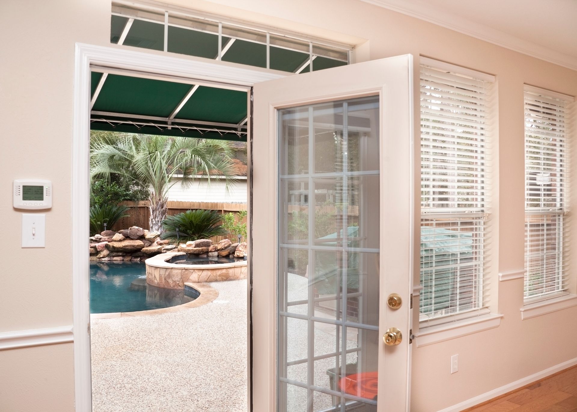 A patio door is open to a backyard with a pool.