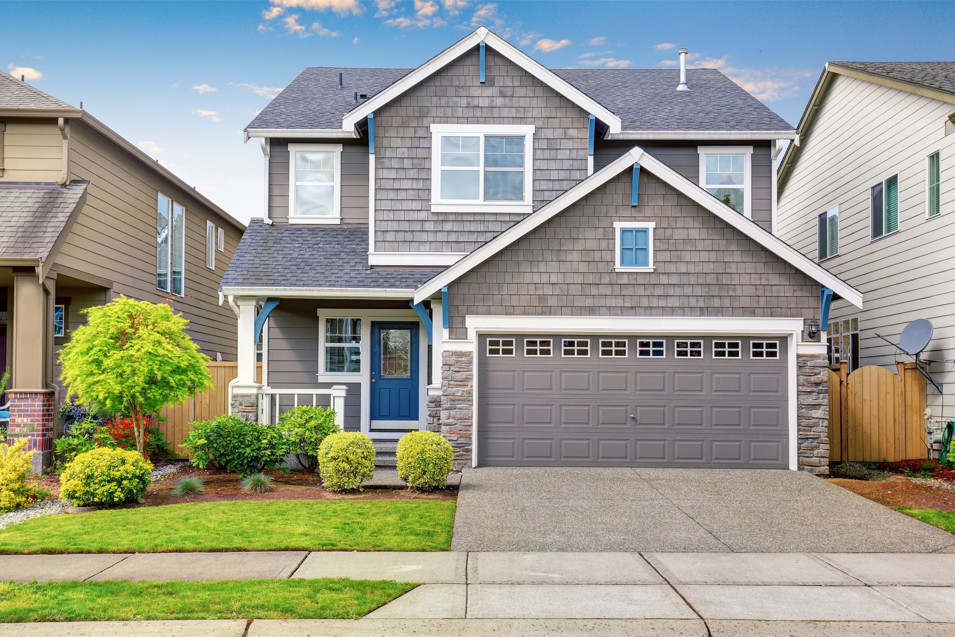 A large gray house with a blue door and a garage.