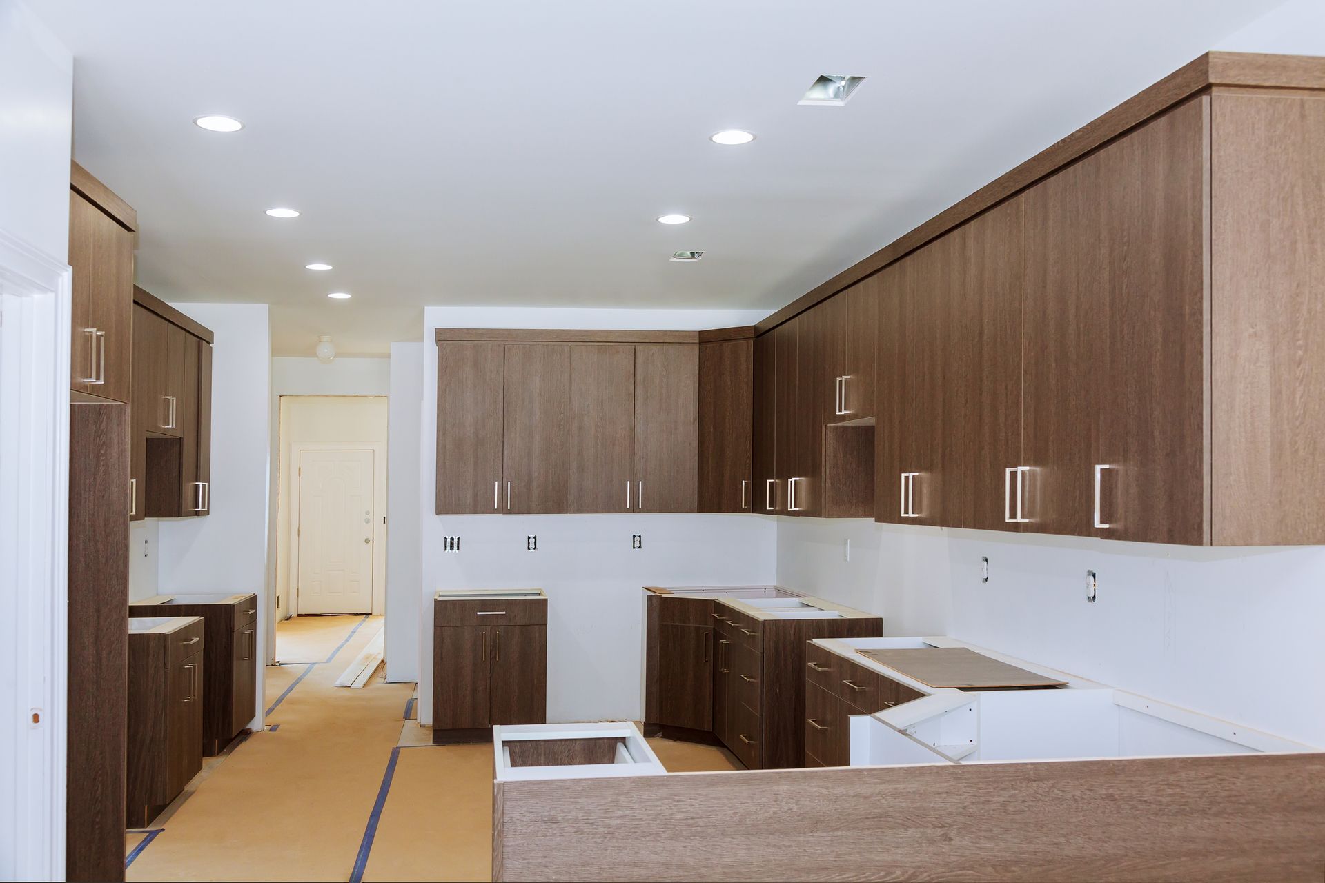 A kitchen under construction with wooden cabinets and white counter tops.