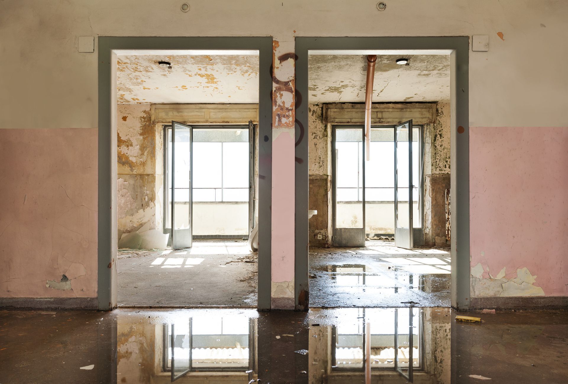 An empty room with a puddle of water between two doors