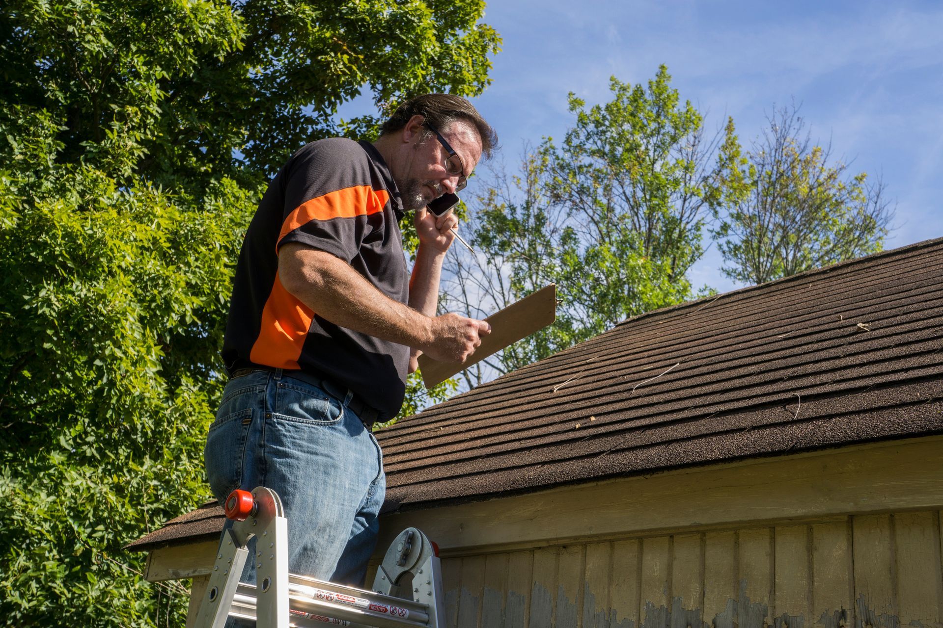 A man is sitting on a ladder looking at a piece of paper.
