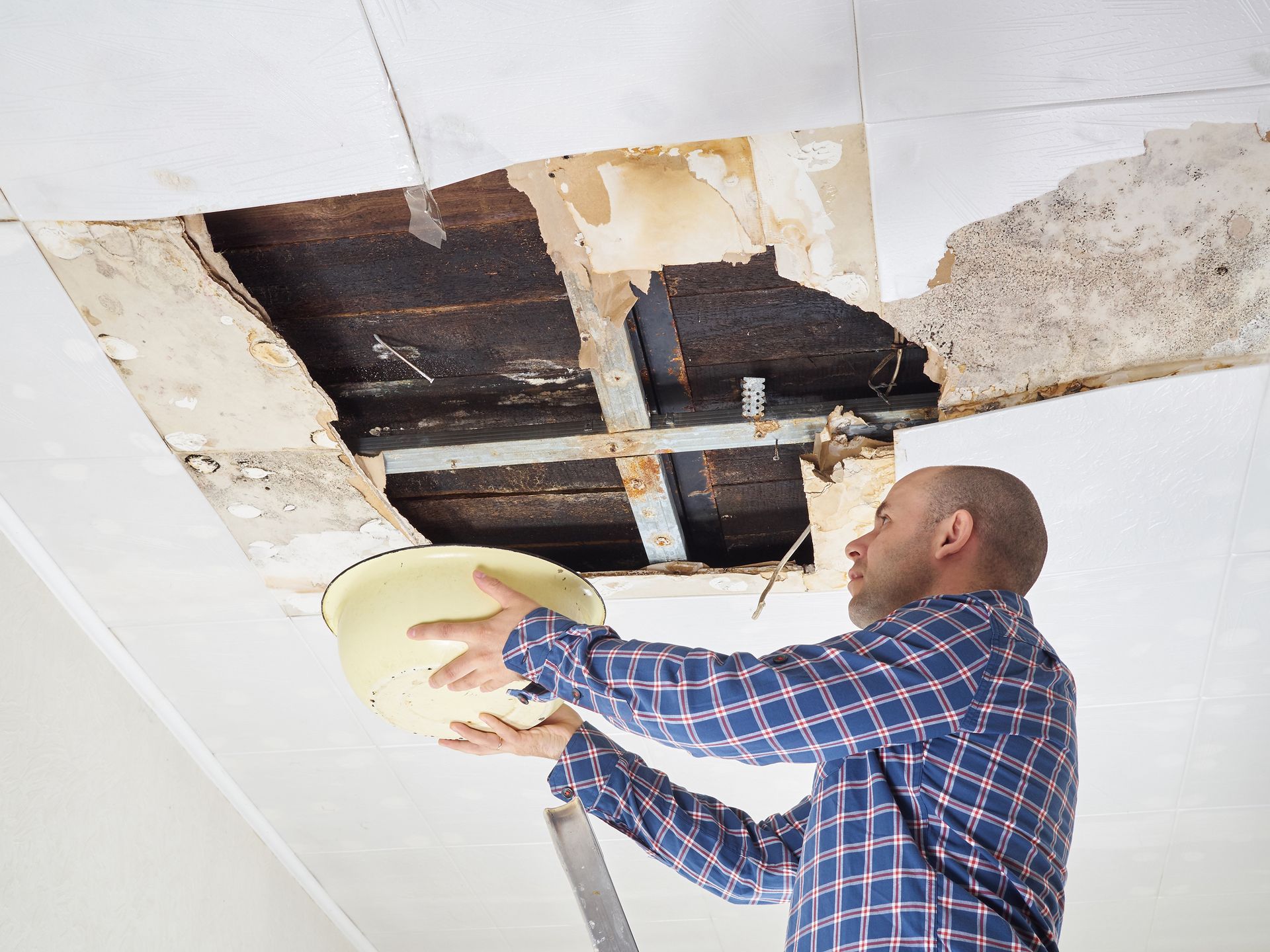 A man is looking through a hole in the ceiling.