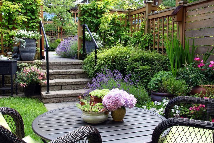 A table and chairs in a garden with flowers on it.