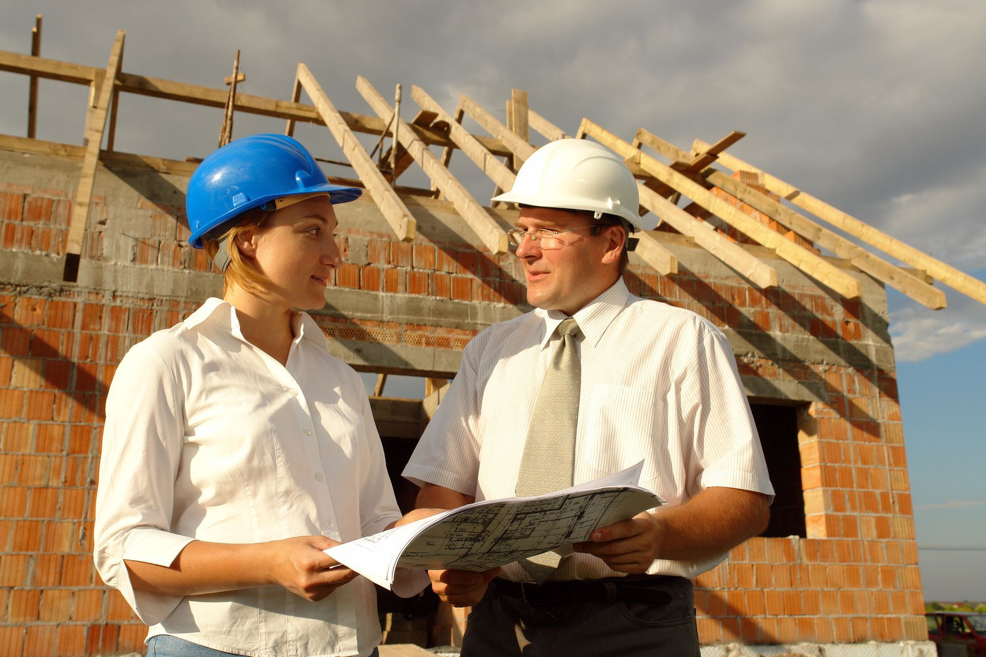 A man and a woman are standing in front of a building under construction