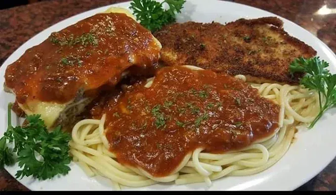 Plate of spaghetti with meat covered in red sauce, and fried meat.