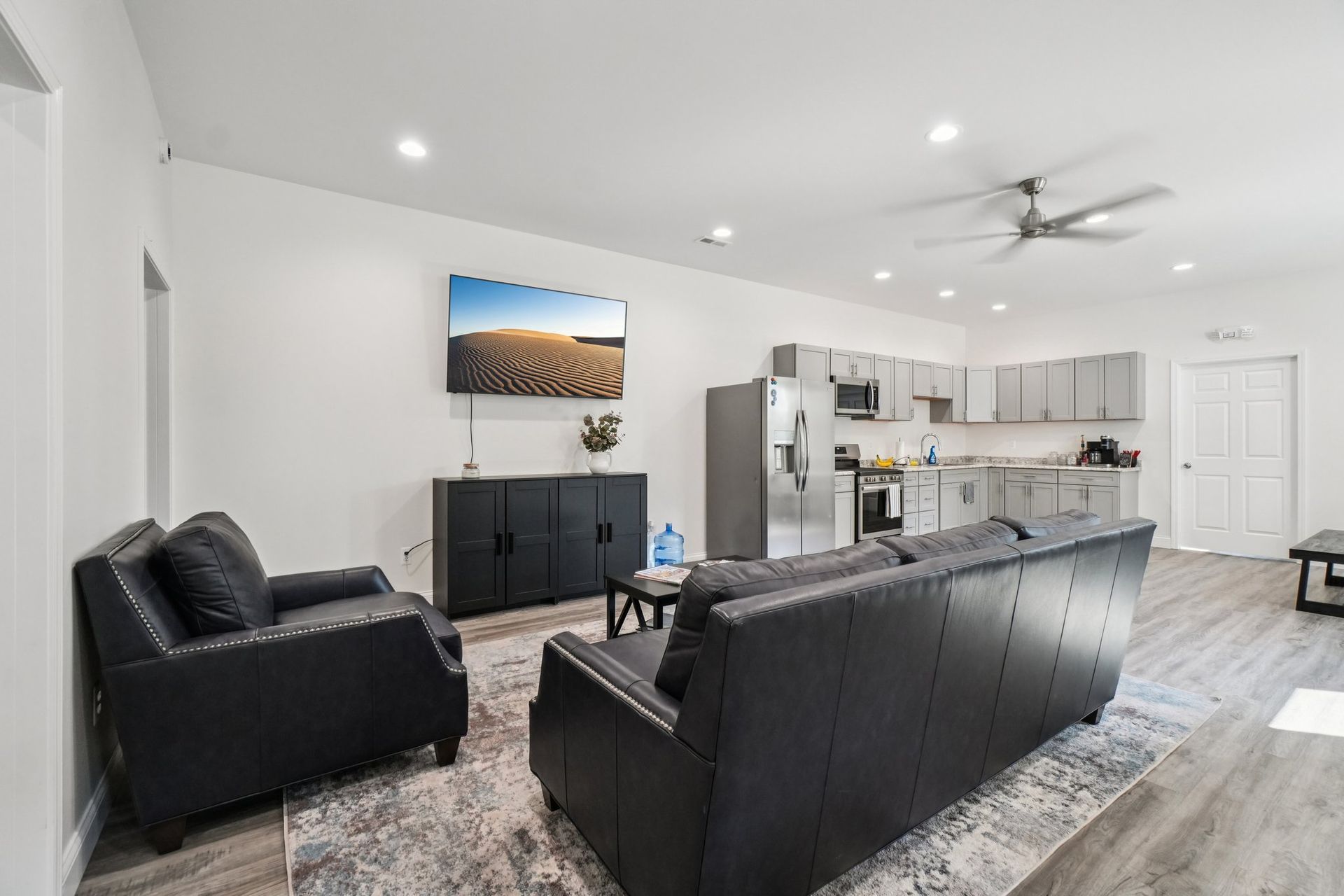 Living room with gray walls, sofa, armchair, TV, kitchen.