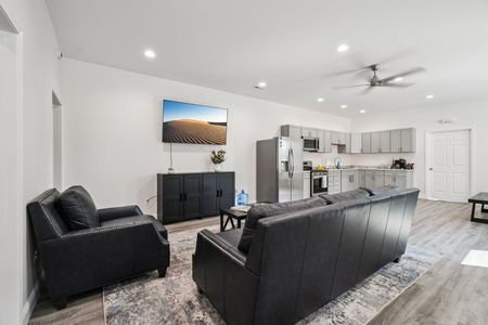 Living room with gray walls, sofa, armchair, TV, kitchen.
