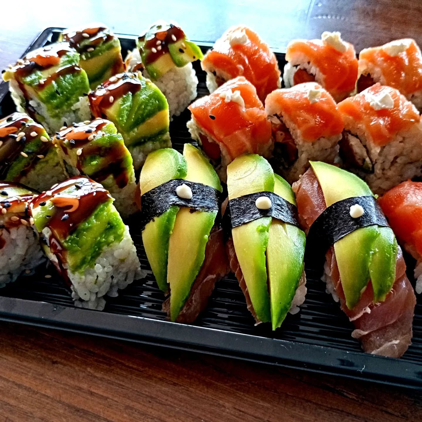 Un vassoio di sushi con avocado e salmone sopra