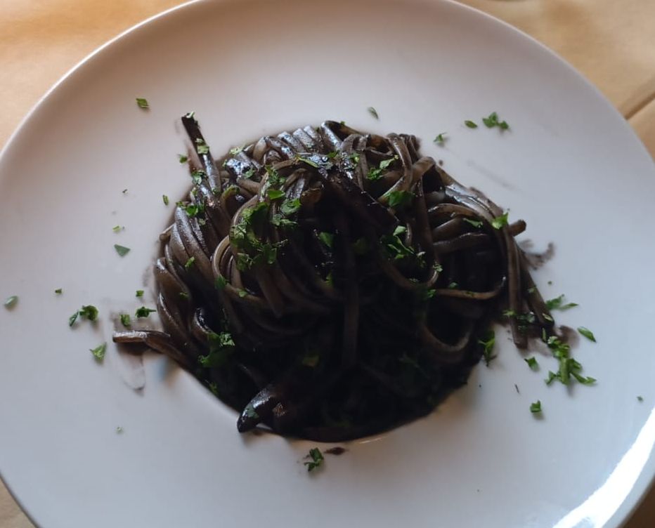 Un piatto bianco con sopra spaghetti e prezzemolo su un tavolo